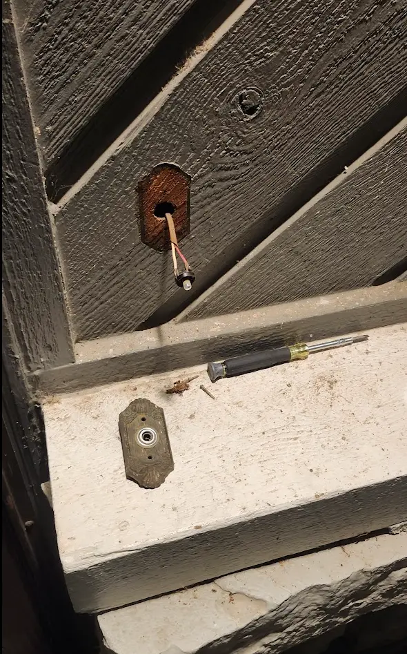 Old doorbell button removed, existing wire visible behind it.