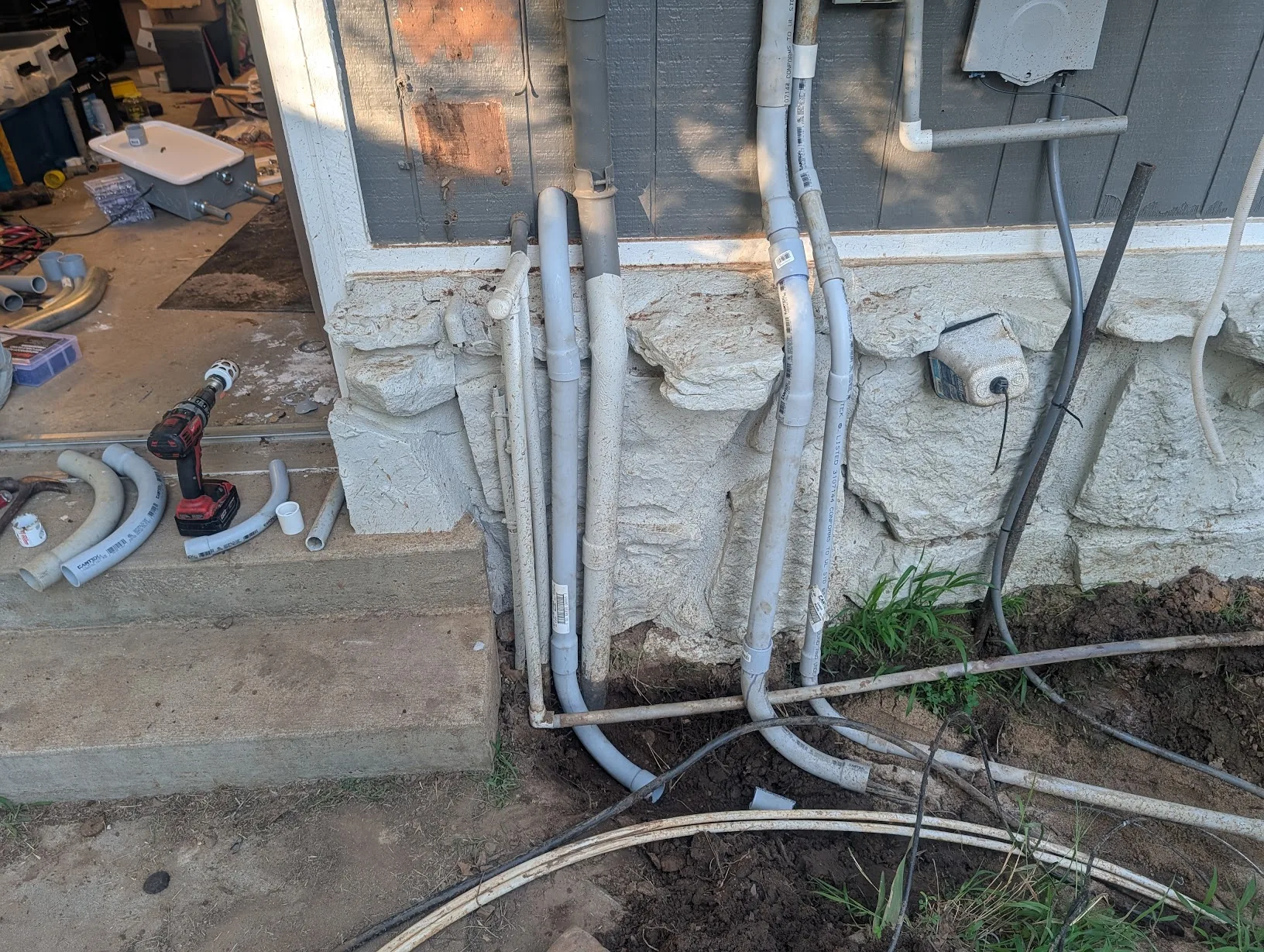 All of the exterior conduit roughed in along the stone wall — PV, shop feeder, and the new low 2" run for comms/etc