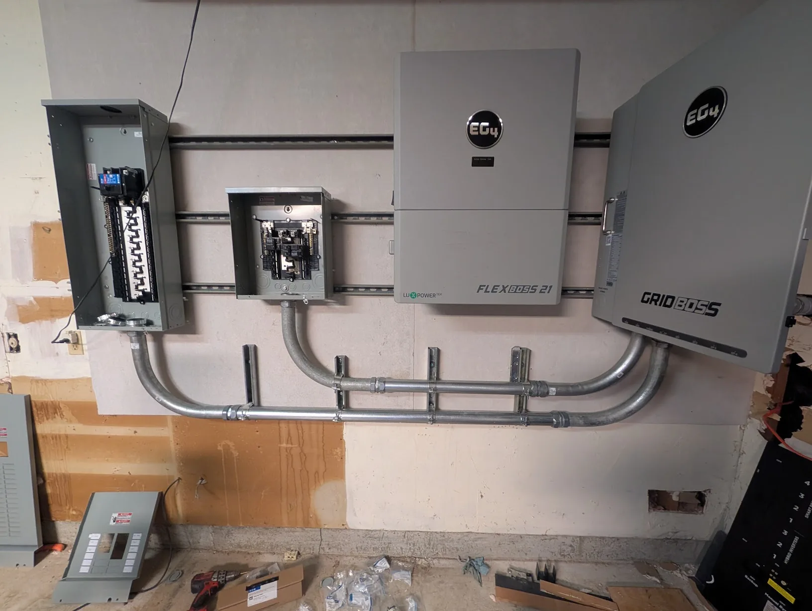 Garage wall with all of the conduit secured to the wall via short strut sections and pipe clamps