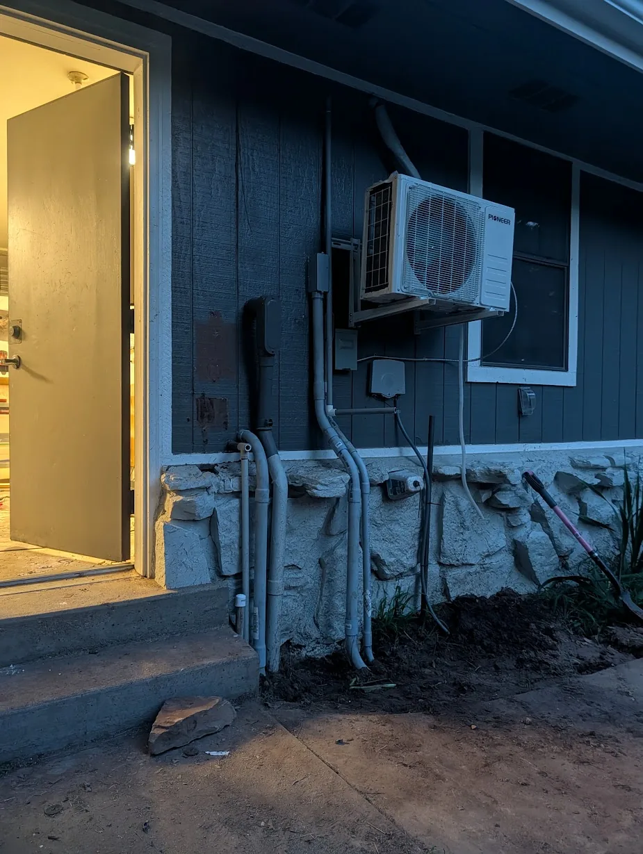 Exterior at dusk — finished conduit run along the wall, ground rod and old disconnected conduit removed