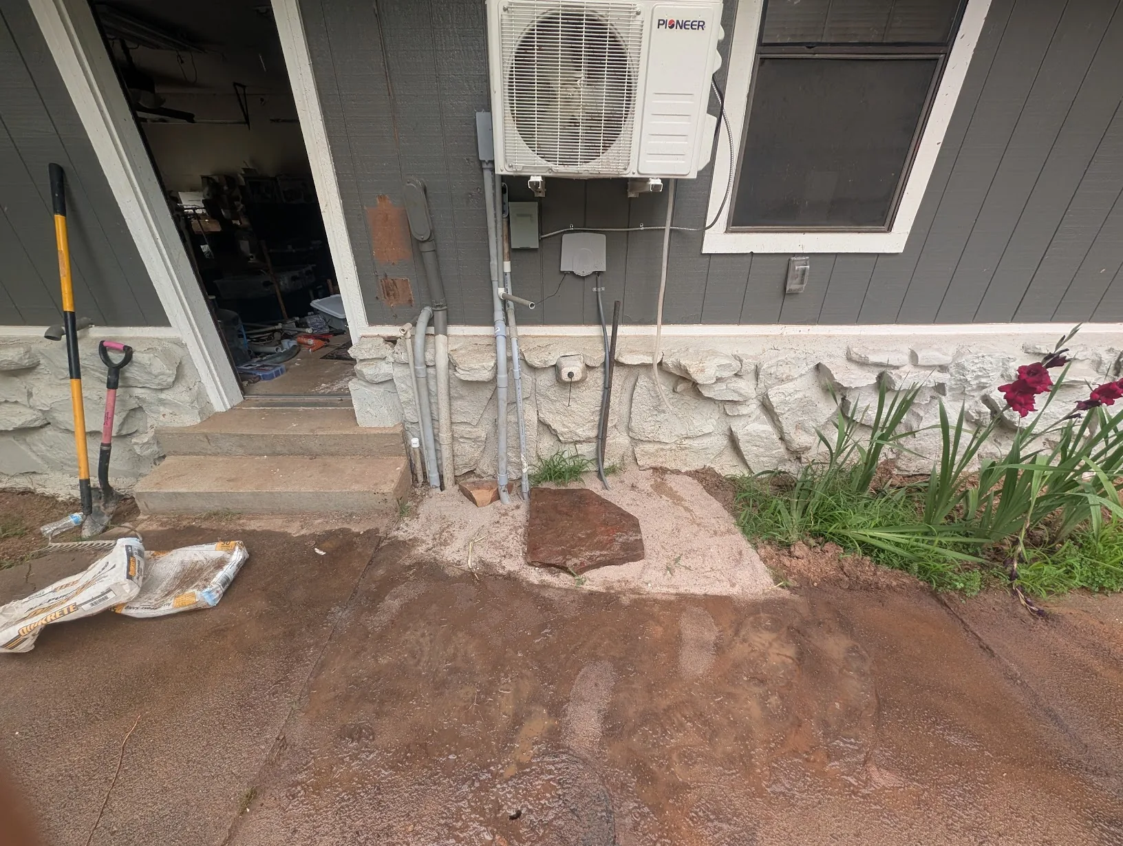 Tidied-up exterior with fresh sand and a large flat rock placed beneath the conduit run