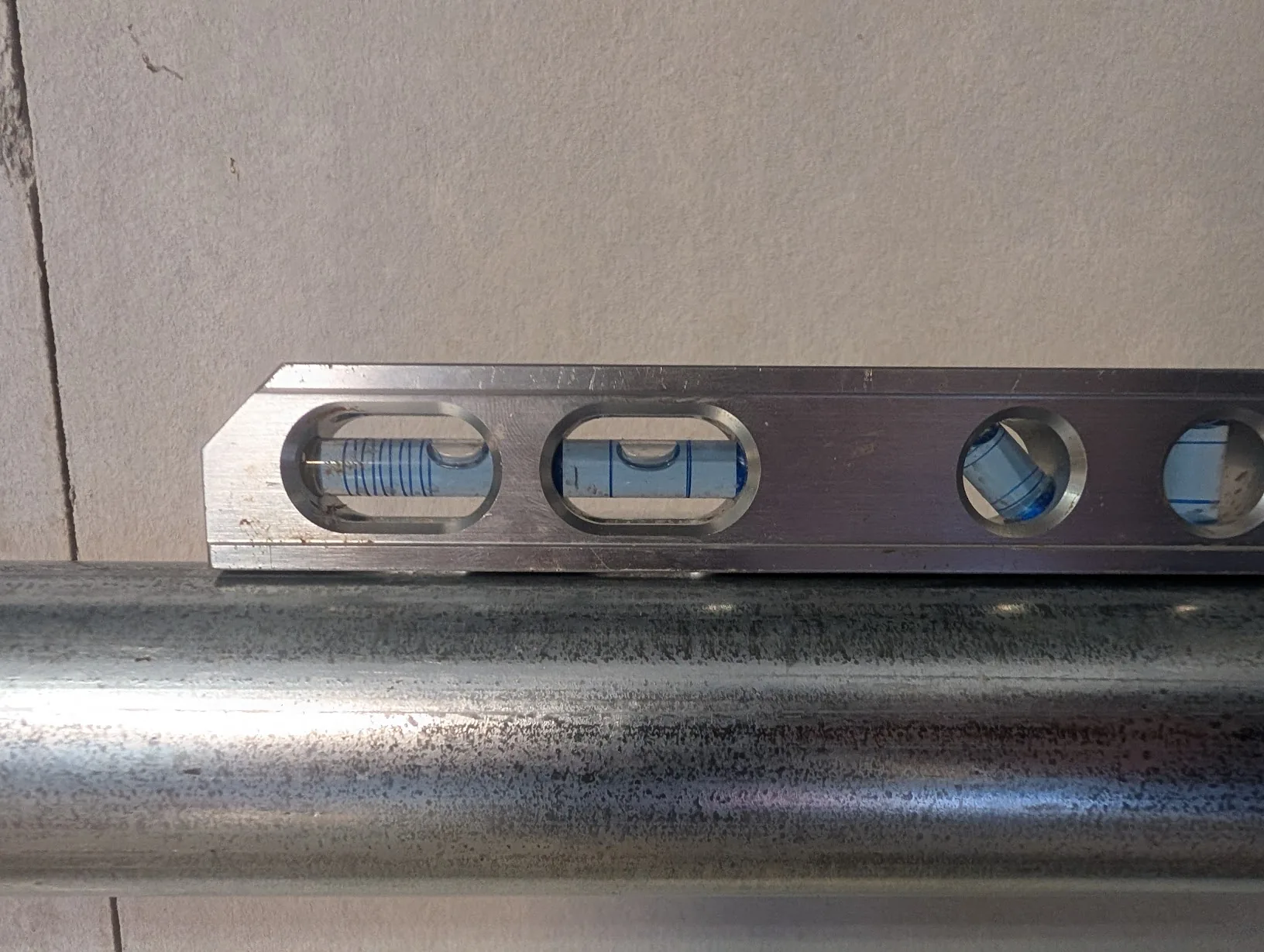 Torpedo level resting on top of the first cut piece of EMT, showing it dead level