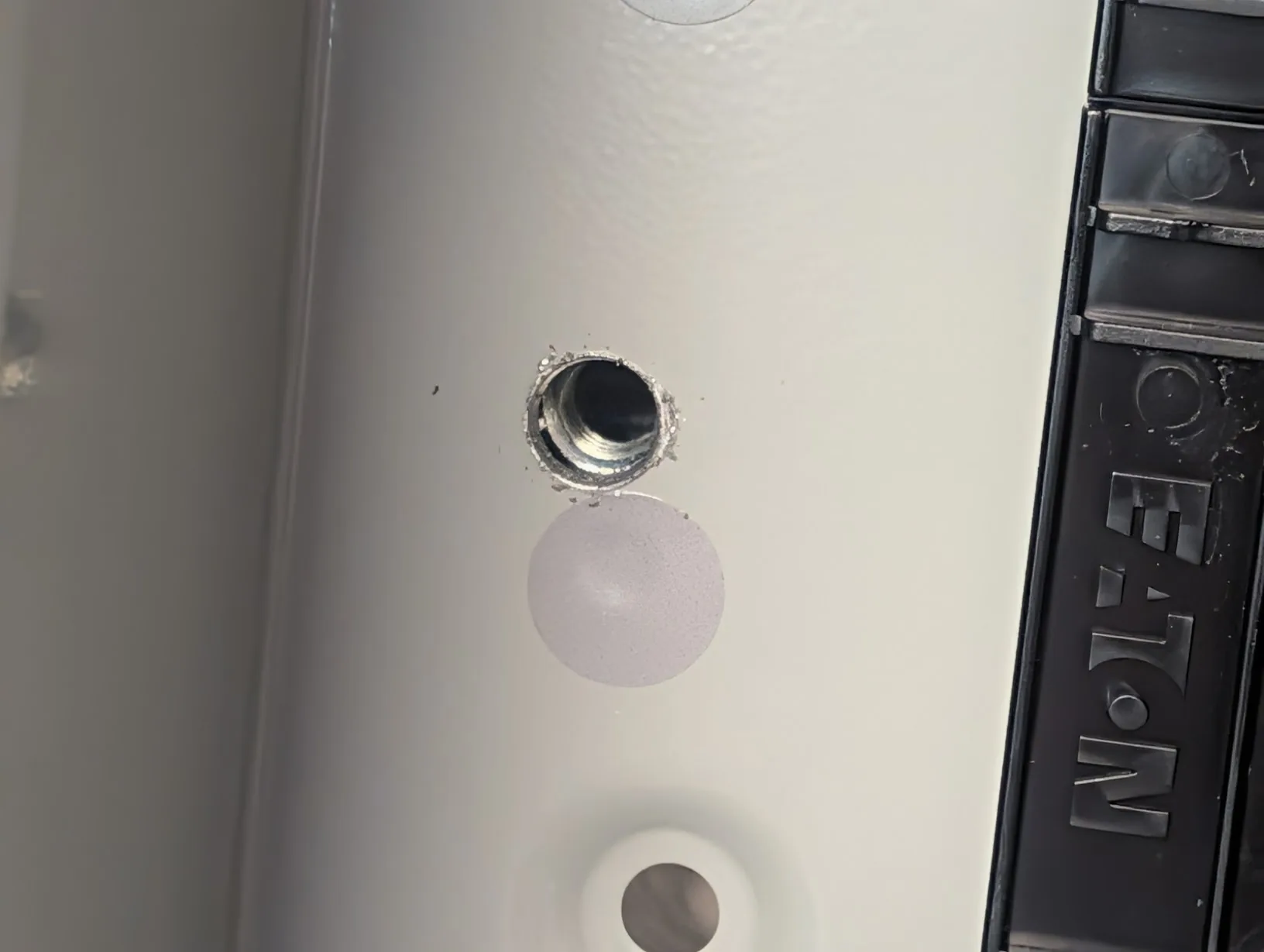 Freshly drilled hole through the panel back, aligned with the lower strut rail