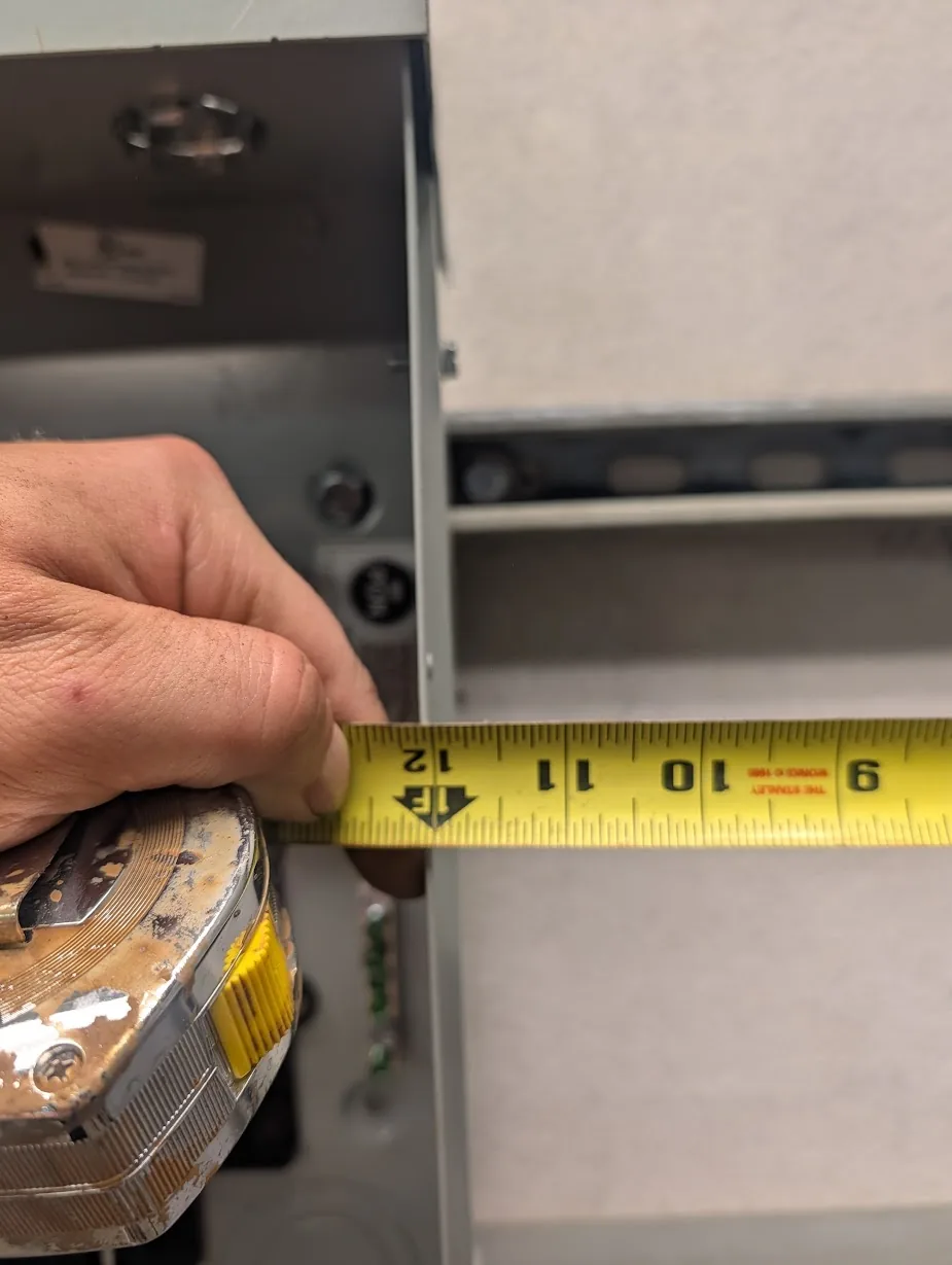 Tape measure between the main panel and subpanel showing exactly 12" of spacing