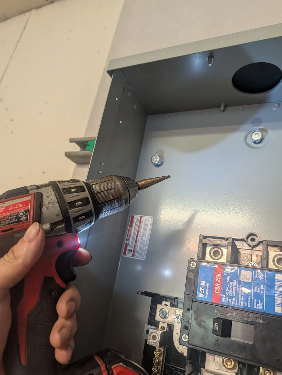 Cordless drill with a step bit enlarging the panel's mounting holes