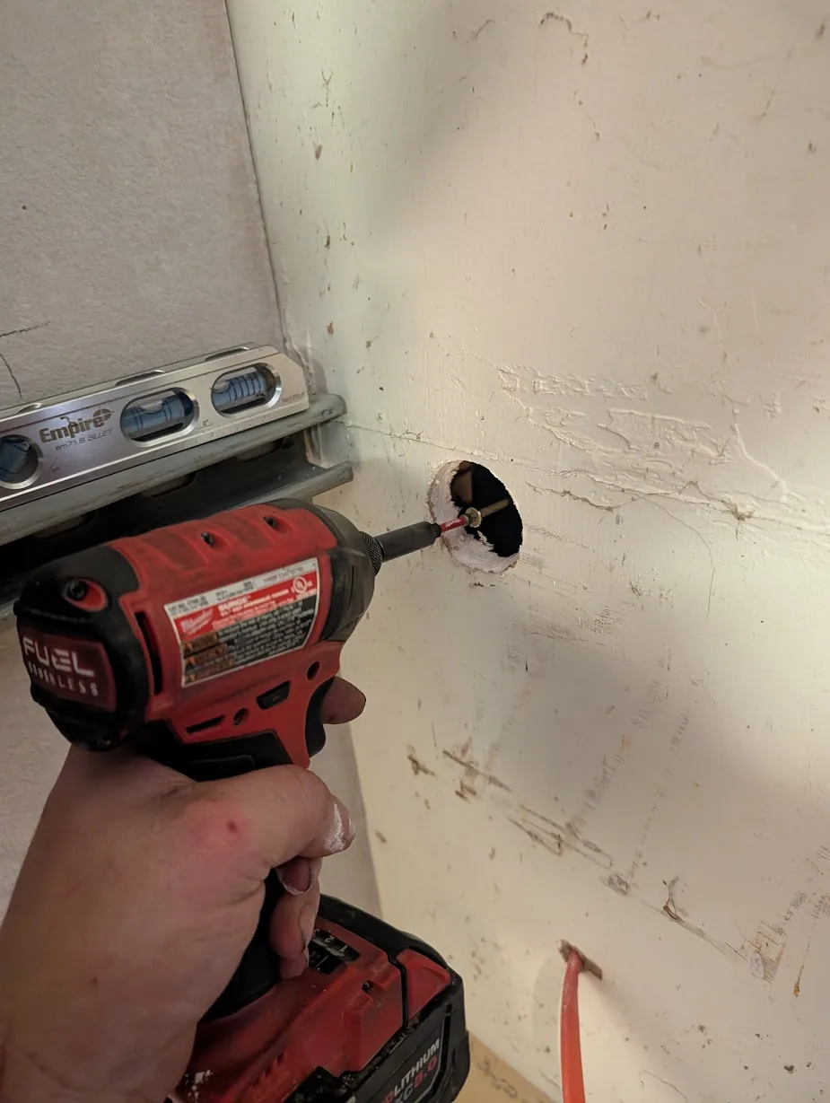 Drilling the feeder hole through the interior sheetrock with a Milwaukee hole saw
