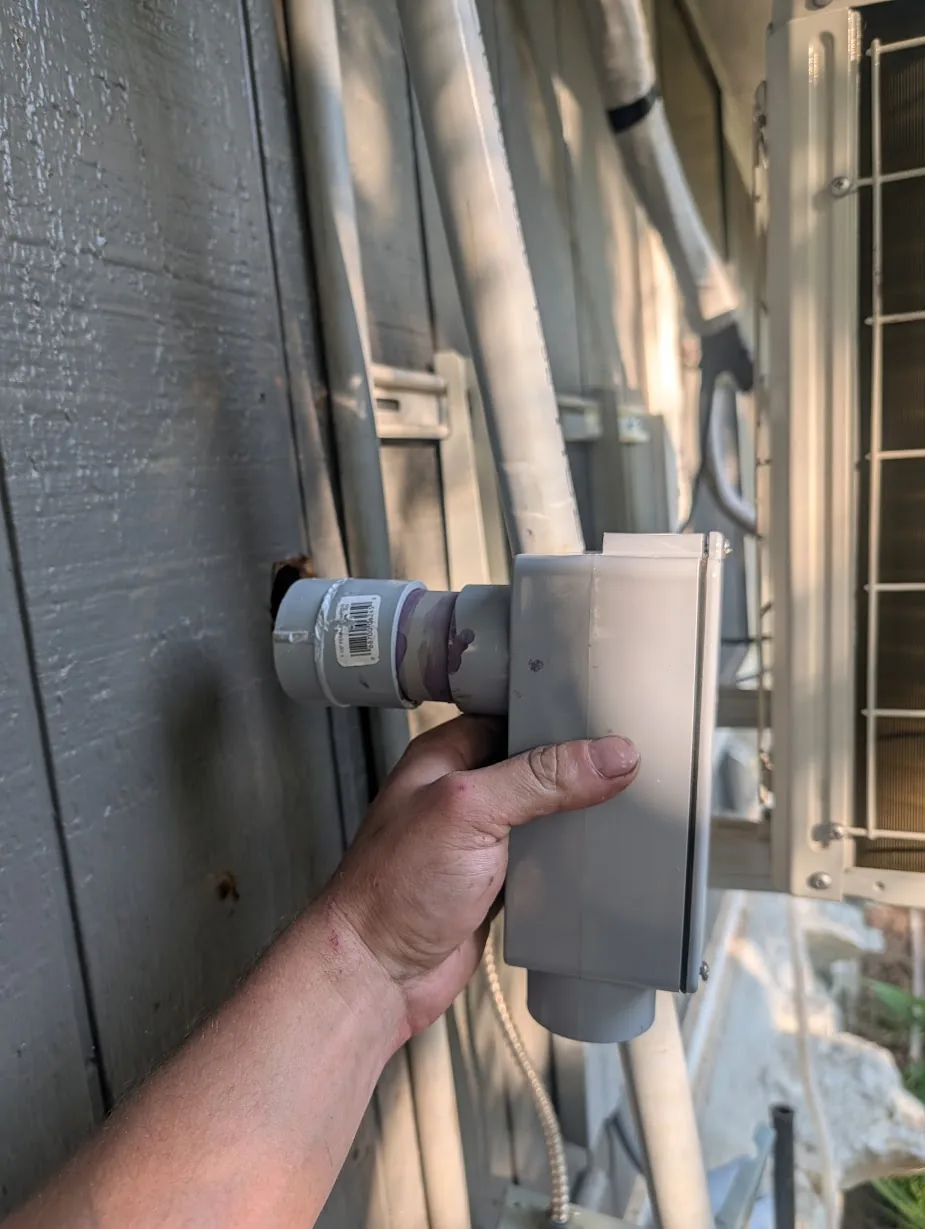 Test-fitting the 1.5" female adapter into the hole in the exterior wall