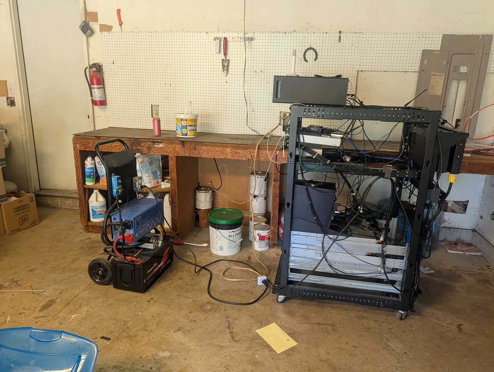Server rack in its original garage workshop position, in front of the pegboard wall