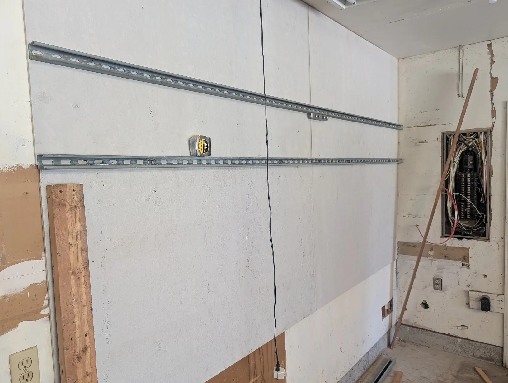 Two strut rails mounted on the wall with a tape measure confirming 1ft spacing