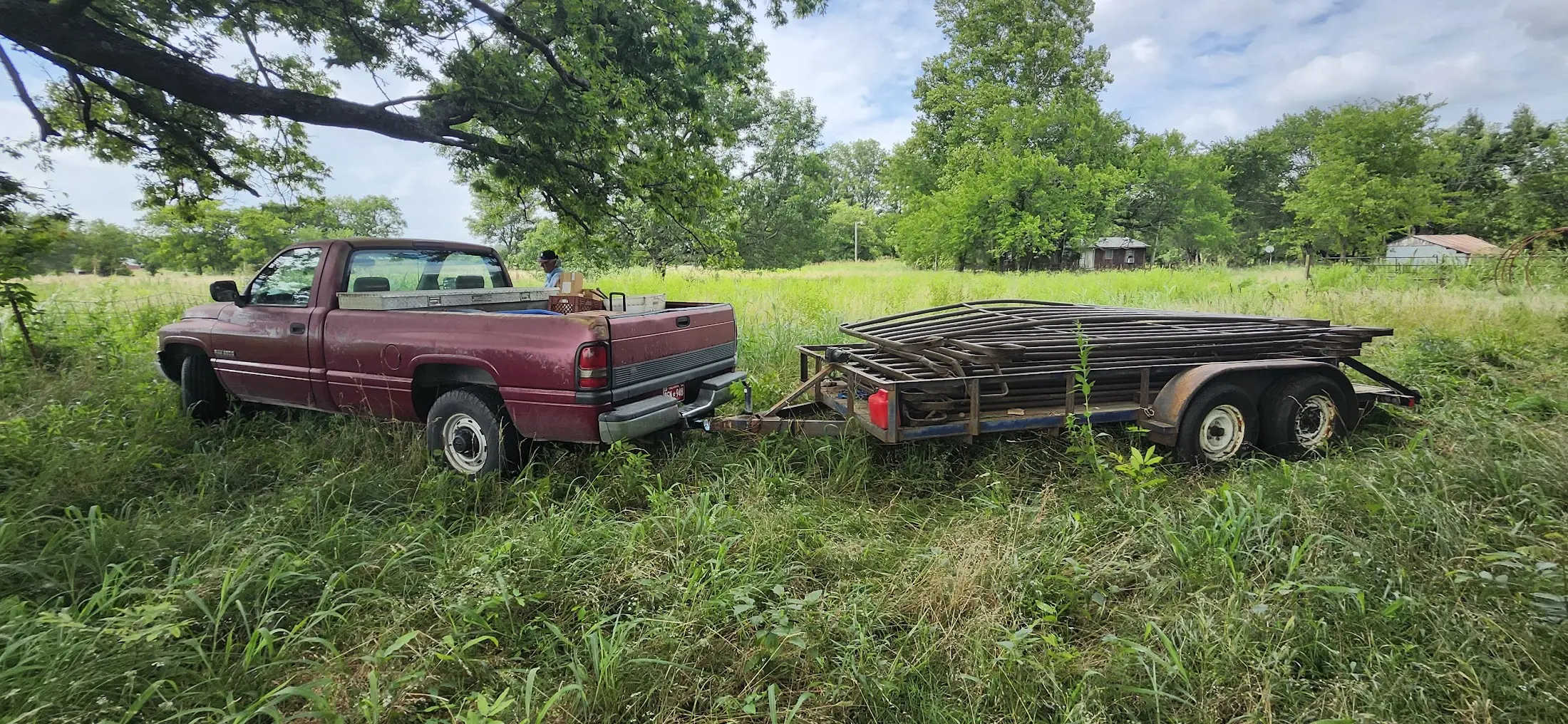Picture of the truck hauling a tailor loaded with fence in an overgrown field.