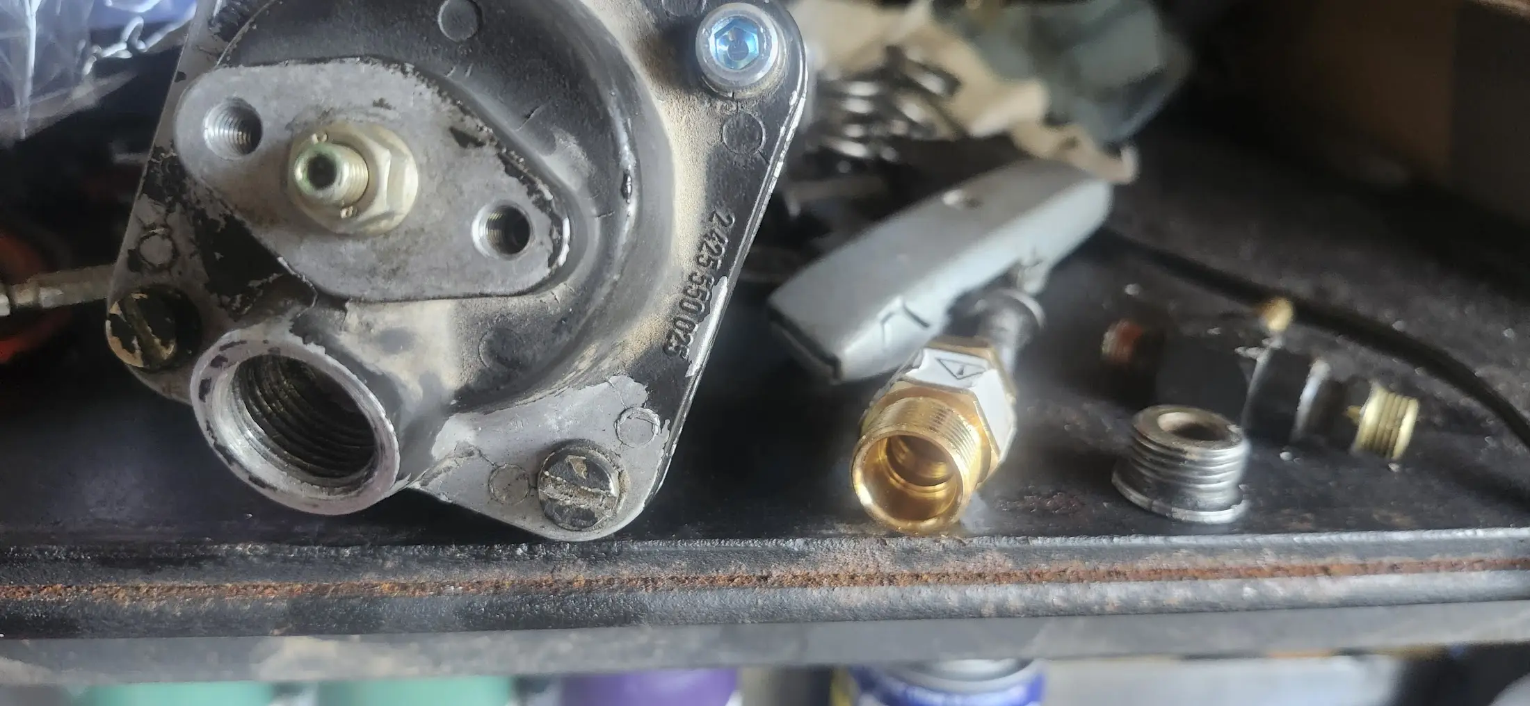 Picture of work table with AFC sitting on left, with air fitting removed. New brass fitting in the middle. Original fitting on the right. Threads are slightly marred