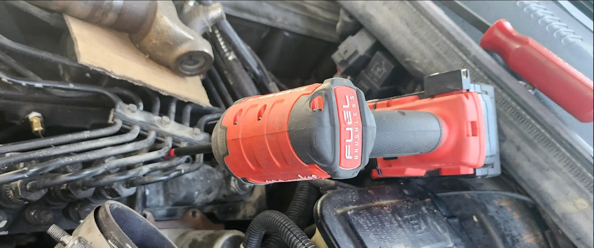 Image showing me removing the security screw with an impact driver snaked between the injector fuel lines