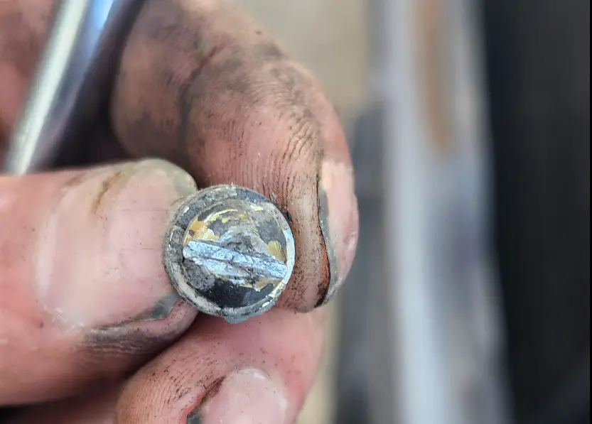 Picture showing the security bolt removed, in my hand, with a well defined slot for a flathead screwdriver