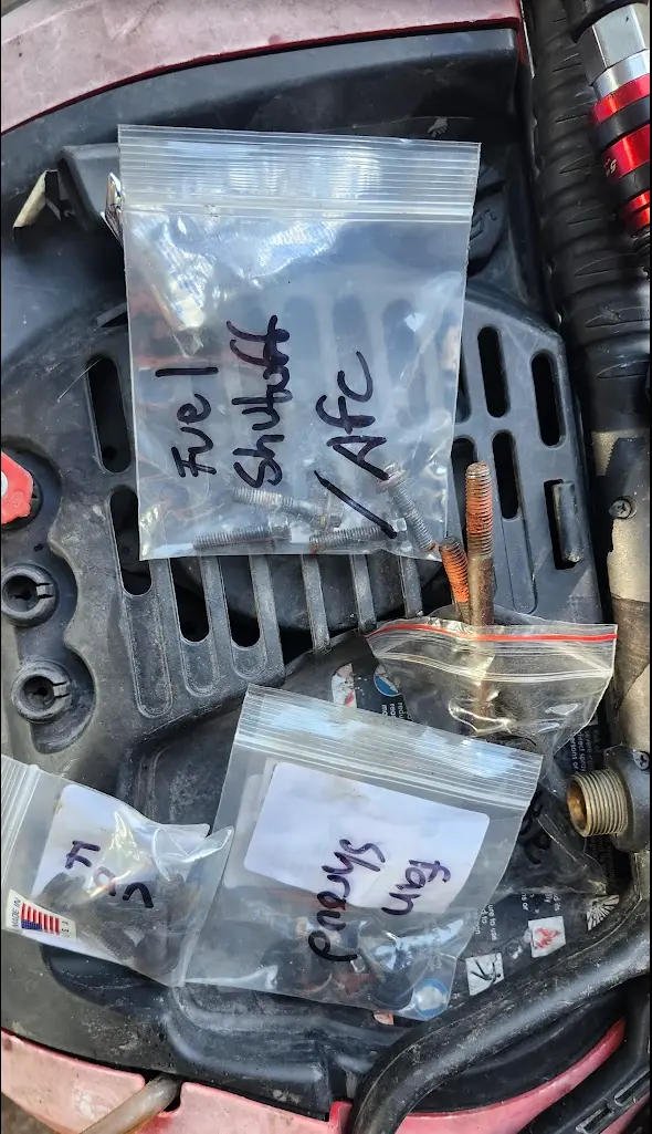 An image showing multiple bags of bolts with labels like fan should, fan, fuel shutoff/afc