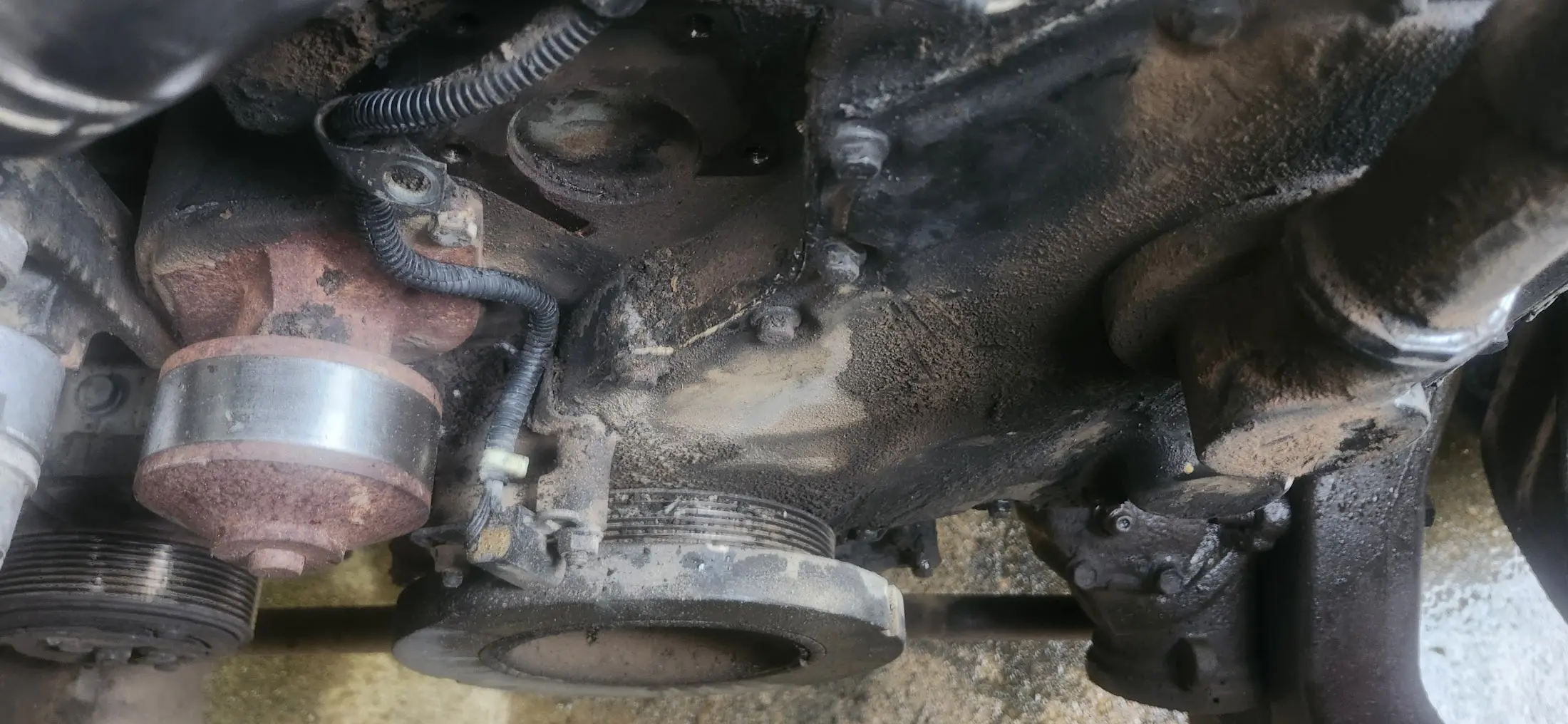 Picture of the front of the engine, without the fan in the way showing the timing cover, crank sensor, crank pulley.