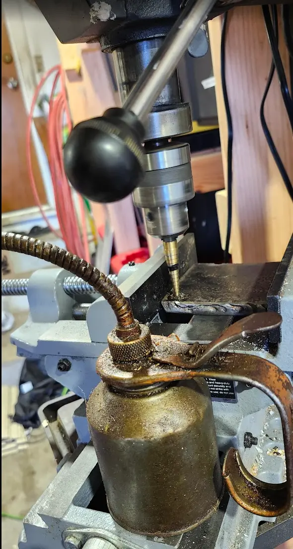Photo showing drill press used to drill holes in plate