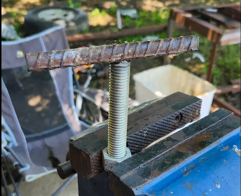 A piece of rebar sitting on a threaded rod, mounted in the vise