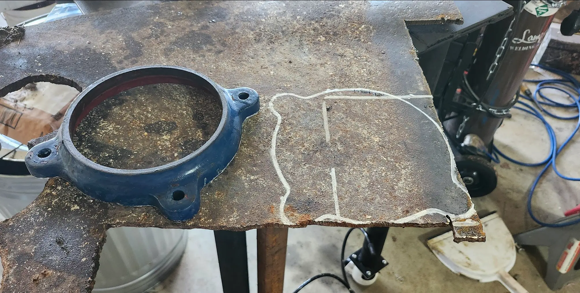 Outline of the vise's base traced onto rusty plate